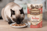 Saszetka 85g mokrej karmy Carnilove Cat Adult Turkey & Valerian Root z grafiką kota i indyka na tle korzenia kozłka lekarskiego.