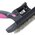 Różowa szczotka samoczyszcząca Buster w rozmiarze M z miękkimi metalowymi szpilkami i przyciskiem do szybkiego usuwania sierści.